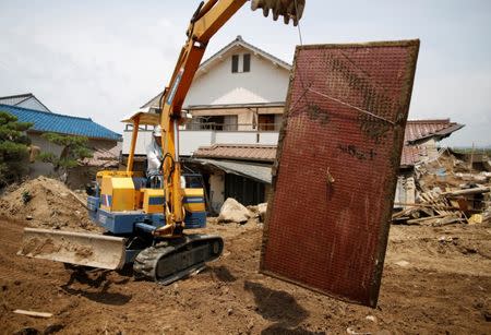 A local resident tries to remove a muddy Japanese tatami mat from his destroyed house at a flood affected area in Mabi town in Kurashiki, Okayama Prefecture, July 13, 2018. REUTERS/Issei Kato