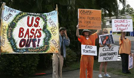 Protesters hold signs as the motorcade of U.S. President Barack Obama returns to Obama's vacation home in Kailua, Hawaii December 28, 2013. REUTERS/Kevin Lamarque