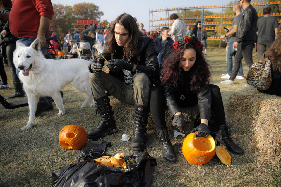 In this Saturday, Oct. 26, 2019 photo people carve Halloween pumpkins at the Halloween Pumpkin Fest in Bucharest, Romania. (AP Photo/Vadim Ghirda)