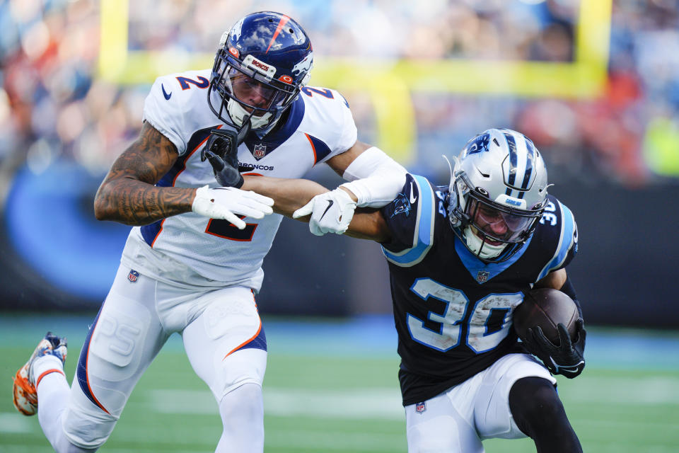 Carolina Panthers running back Chuba Hubbard run past Denver Broncos cornerback Pat Surtain II during the second half of an NFL football game between the Carolina Panthers and the Denver Broncos on Sunday, Nov. 27, 2022, in Charlotte, N.C. (AP Photo/Jacob Kupferman)