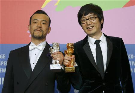 Diao Yinan (R) director of "Bai Ri Yan Huo" (Black Coal, Thin Ice) poses with his Golden Bear for Best Film next to actor Liao Fan (L) who poses with his Silver Bear for Best Actor during a news conference after the awards ceremony of the 64th Berlinale International Film Festival in Berlin February 15, 2014. REUTERS/Thomas Peter