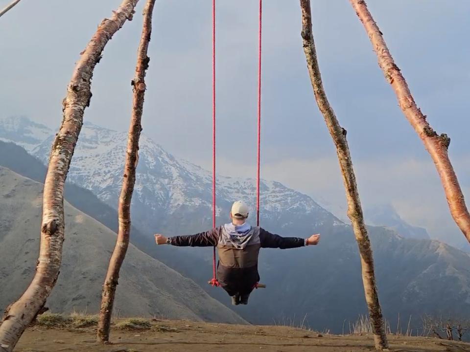 a man on a swing overlooking the himalayas in nepal