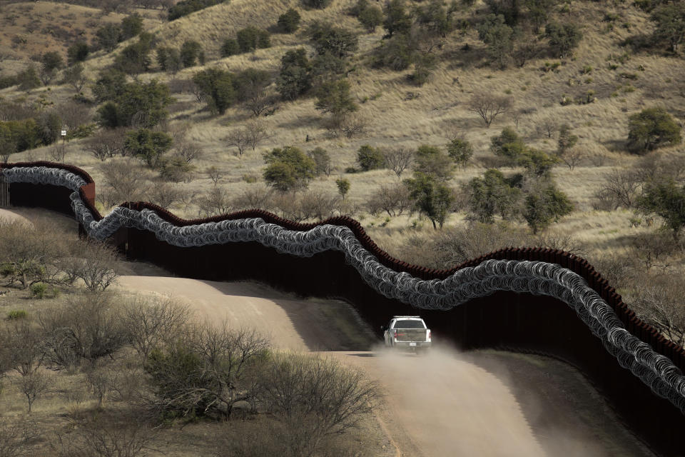 FILE - In this March 2, 2019, file photo, a Customs and Border Control agent patrols on the U.S. side of a razor-wire-covered border wall along Mexico east of Nogales, Ariz. After a record hot and dry summer, more deaths among border-crossers have been documented in Arizona's desert and mountains. (AP Photo/Charlie Riedel, File)