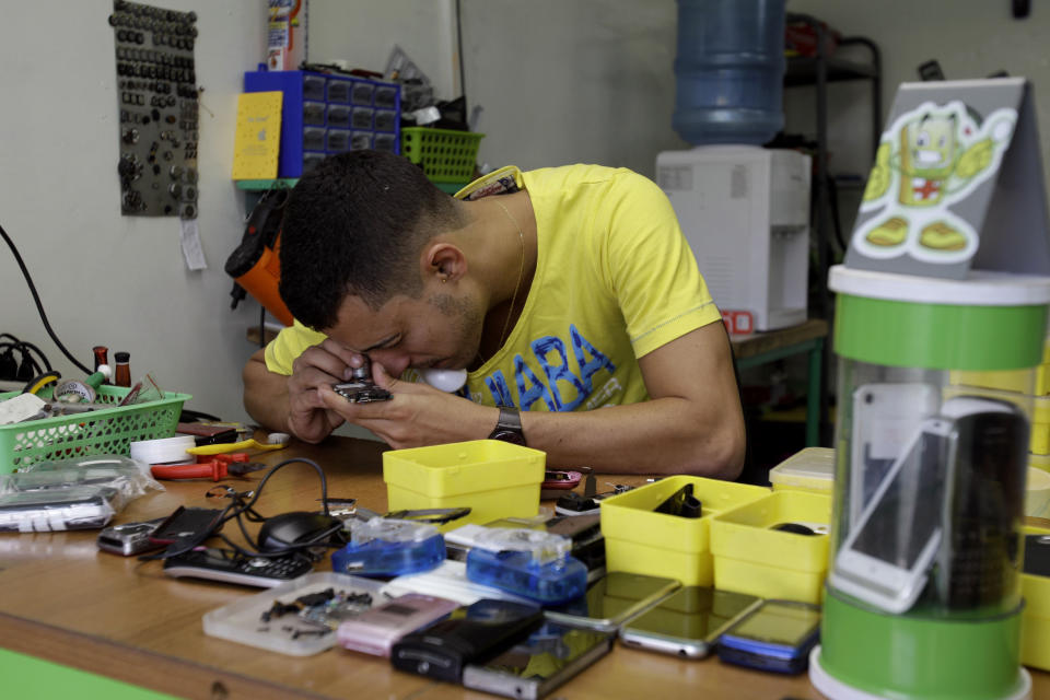 In this Aug. 30, 2012 photo, Javier E. Matos repairs a cell phone at The Cell Phone Clinic, a private business in Havana, Cuba. A jump in import taxes on Monday, Sept. 3 threatens to make life tougher for some of Cuba's new entrepreneurs who the government has been trying to encourage as it cuts a bloated workforce in the socialist economy. In Cuba, the average monthly wage is about $20. (AP Photo/Franklin Reyes)