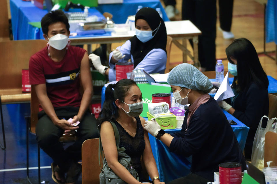 A health worker administers a dose of the AstraZeneca COVID-19 vaccine to a woman in Bangkok, Thailand, Wednesday, Feb. 23, 2022. Thailand will ease some entry requirements for foreign visitors as it balances a rising number of coronavirus cases with the need to rebuild its pandemic-damaged economy, the government announced Wednesday.(AP Photo/Sakchai Lalit)