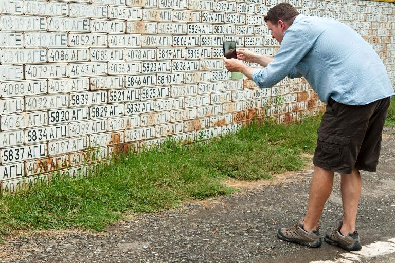A tourist takes a picture of fence of old car numbers in Vank village in Armenian-controlled Azerbaijani region of Nagorny Karabakh on June 27, 2013