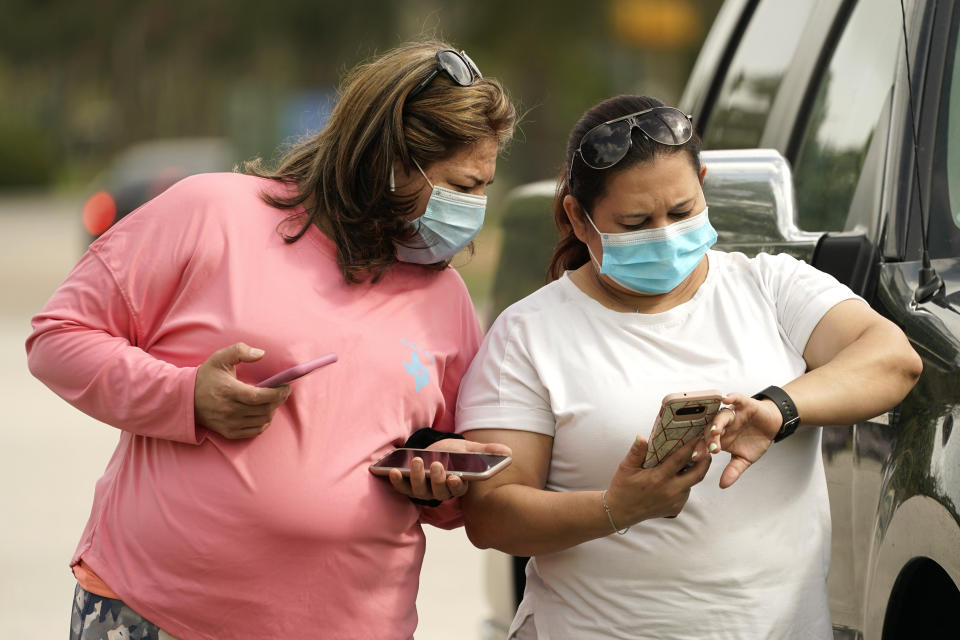 Women wear masks as they check a mobile phone Wednesday, July 1, 2014, in Houston. Harris County Commissioners have voted to extend the recently-issued mask order until August 26. The order directs any businesses providing goods or services to require all employees and visitors to wear face coverings in areas of close proximity to co-workers or the public. (AP Photo/David J. Phillip)