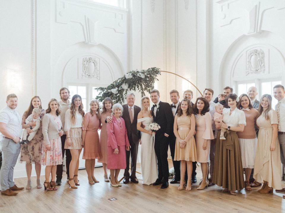 couple taking a group photo with their extended families on their wedding day