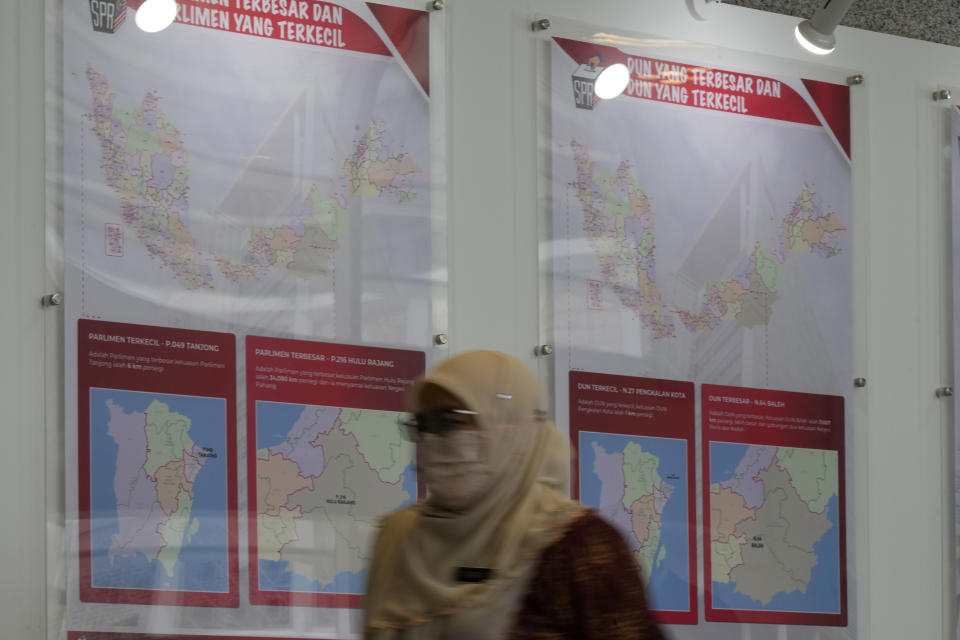 A staff member from Malaysia's Election Commission walks past a map showing state assembly areas an so on, at its office in Putrajaya, Malaysia Thursday, Oct. 20, 2022. Malaysia's Election Commission said Thursday that national elections will be held on Nov. 19, amid concerns that heavy rain and floods during the year-end monsoon season may deter voters. (AP Photo/Vincent Thian)