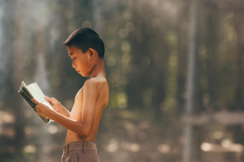 Rural children are reading a book at the forest.Book knowledge is important for Genes in the rural areas of Asia.