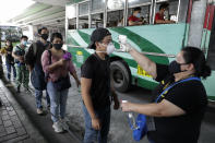 People have their temperatures checked before boarding a bus during the first day of a more relaxed lockdown that was placed to prevent the spread of the new coronavirus in Manila, Philippines on Monday, June 1, 2020. Traffic jams and crowds of commuters are back in the Philippine capital, which shifted to a more relaxed quarantine with limited public transport in a high-stakes gamble to slowly reopen the economy while fighting the coronavirus outbreak. (AP Photo/Aaron Favila)