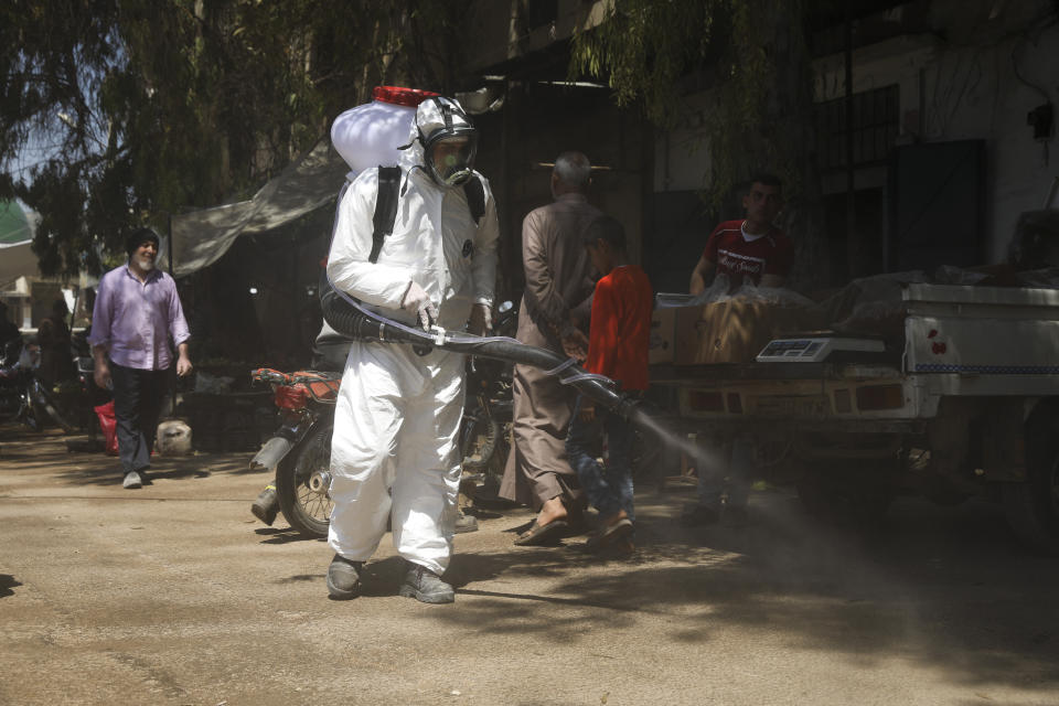 FILE - In this Tuesday, April 14, 2020 file photo, a member of a non-governmental aid organization spray disinfectant as a preventive measure for coronavirus in the town of Armnaz, Idlib province, Syria. Wealthier Western countries are considering how to ease lockdown restrictions and start taking gradual steps toward reviving business and daily life. But many developing countries, particularly in the Middle East and Africa, can hardly afford the luxury of any misstep. (AP Photo/Ghaith Alsayed, File)