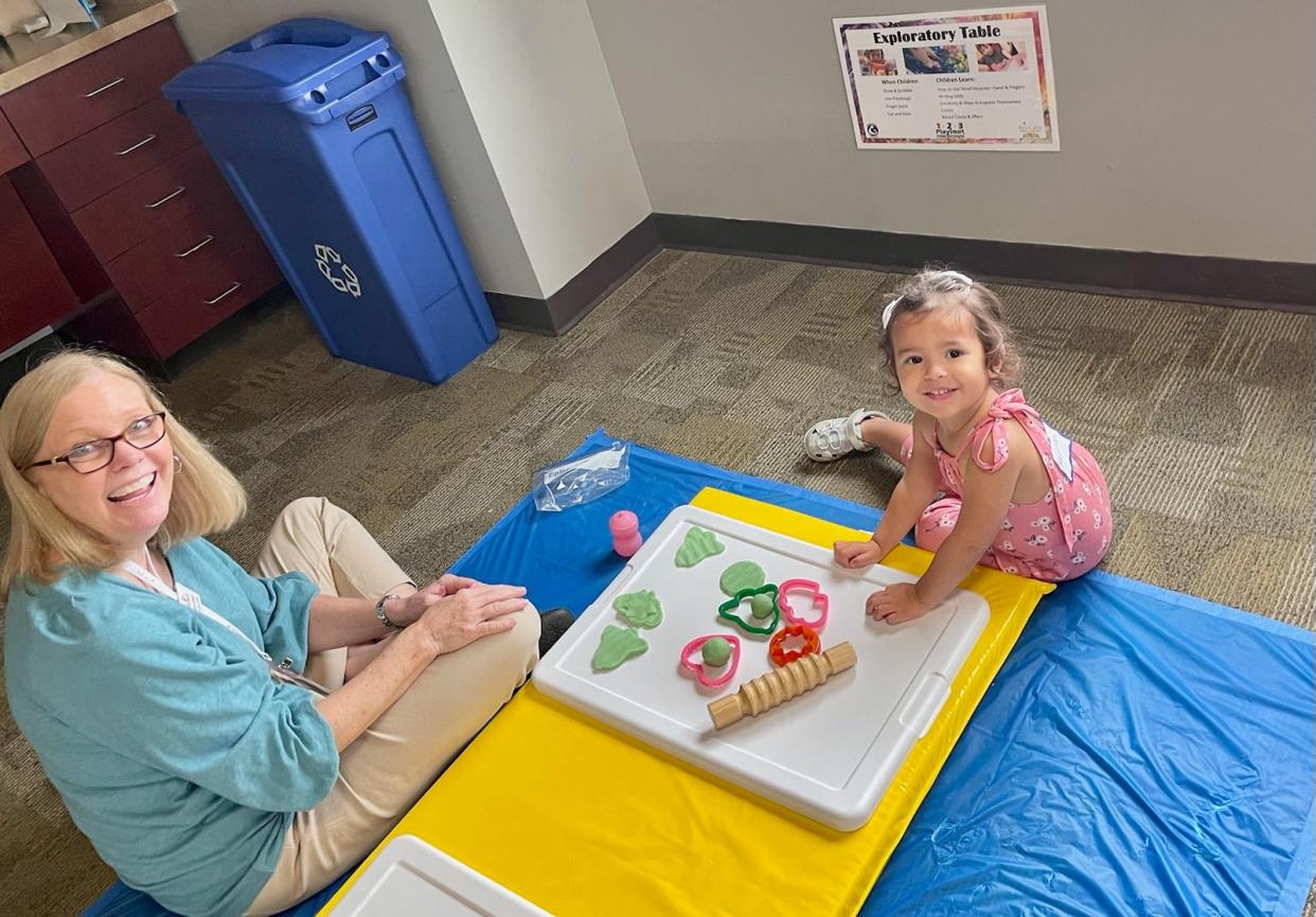 Public services librarian Terry Lewis helps a child with using Play-Doh in the children's area of the Bee Cave Public Library.