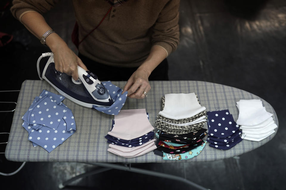 In this Monday, Feb. 17, 2020, photo, a volunteer irons the handmade cotton masks in Hong Kong. Volunteers from a Hong Kong theater group are turning their backstage skills to helping out against the new coronavirus, sewing reusable protective masks for those who can't access or afford them. Jo Ngai, a drama lover and founder of the Nonsensemakers, along with her friend Jessie Han, have turned a theater rehearsal room into a temporary handmade mask factory. (AP Photo/Kin Cheung)