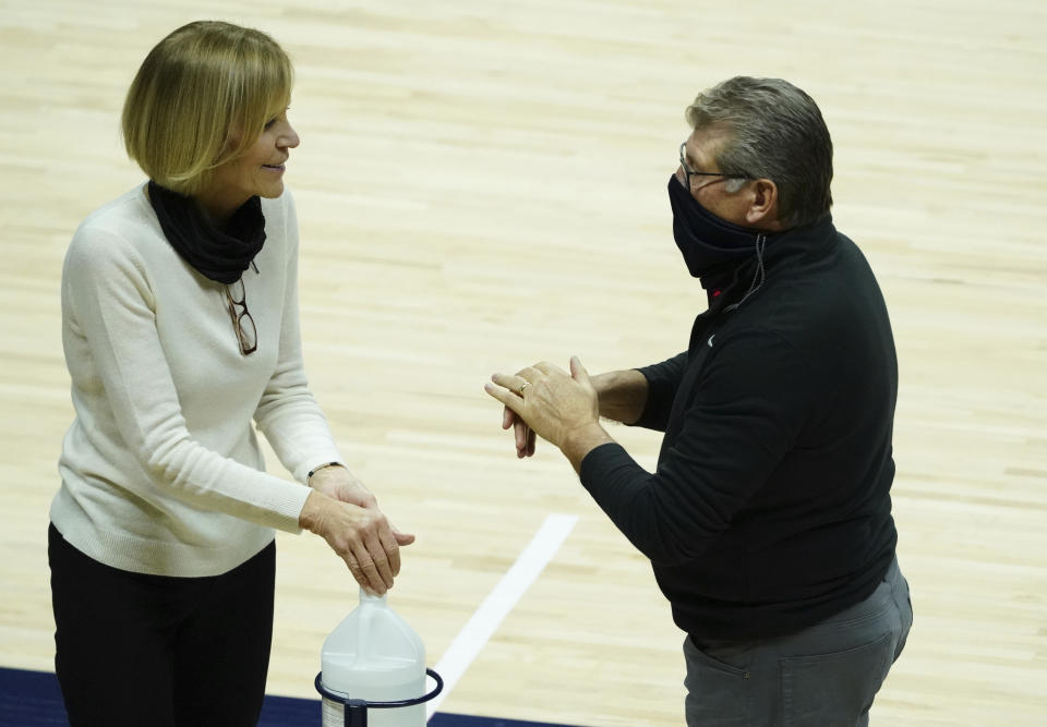 Connecticut head coach Geno Auriemma and associate head coach Chris Dailey sanitize their hands before an NCAA college basketball game against Providence at Harry A. Gampel Pavilion, Saturday, Jan. 9, 2021, in Storrs, Conn. (David Butler II/Pool Photo via AP)
