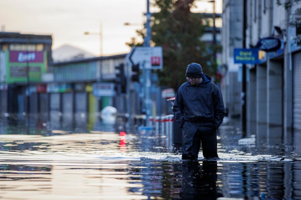 Michael McShane walks through flood water on Market Street in Downpatrick (Gareth Fuller/PA Wire)
