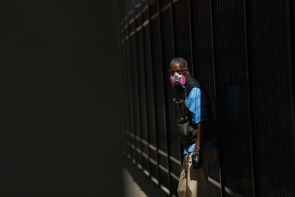 A man wears a protective mask while waiting for a bus in Detroit, Wednesday, April 8, 2020. Detroit buses will have surgical masks available to riders starting Wednesday, a new precaution the city is taking from the new coronavirus COVID-19. (AP Photo/Paul Sancya)