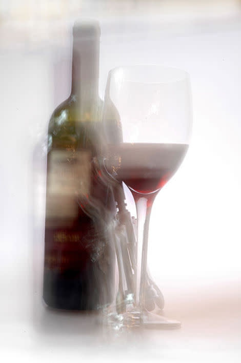 A bottle of wine and a glass are shown in a blurry photo.