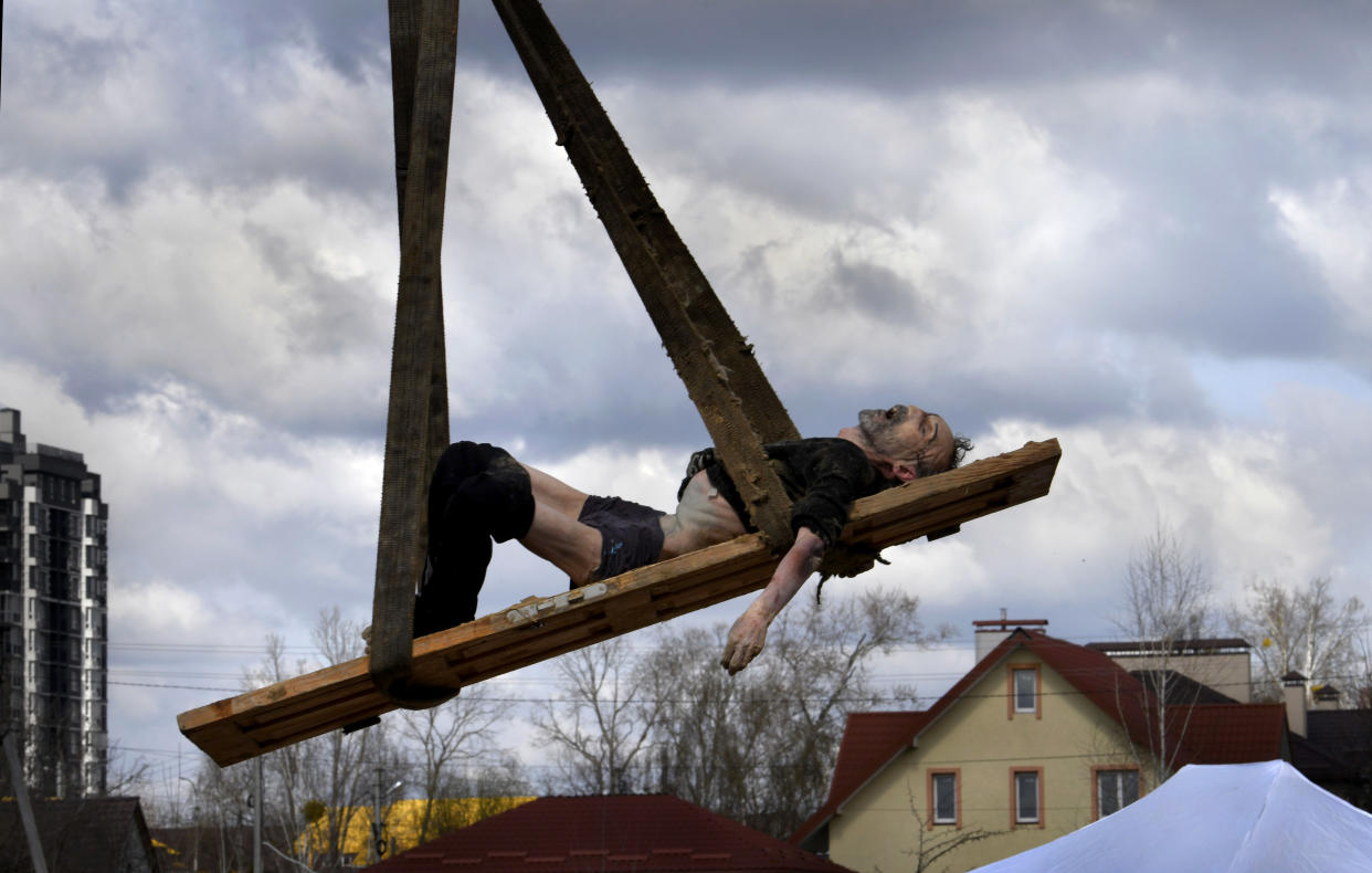 The body of a man is hoisted on a wooden door being used as a makeshift stretcher as investigators recover the bodies of more than 400 civilians slain in Bucha.