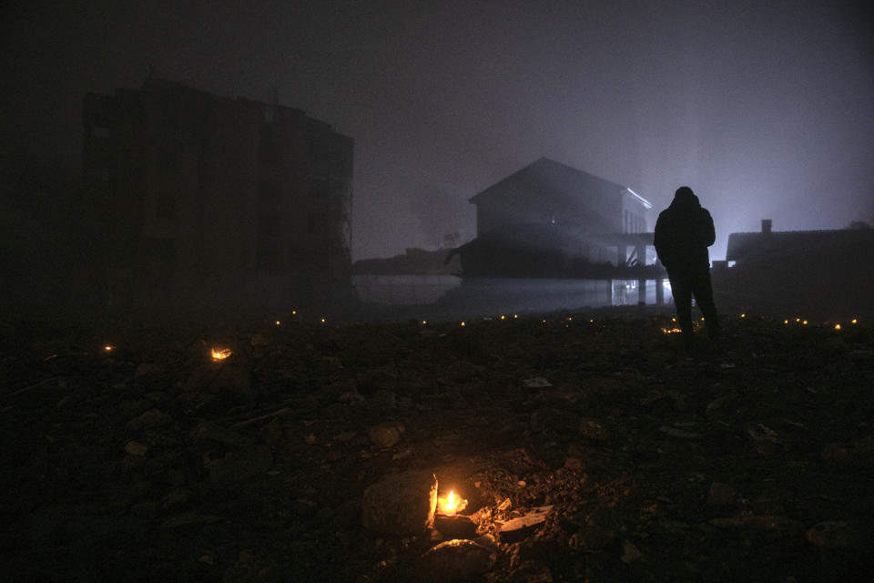 People stand for a moment of silence over the remains of the destroyed buildings, marking the one-year anniversary of the earthquake, in the city of Antakya, southern Turkey, Tuesday, Feb. 6, 2024. Millions of people across Turkey on Tuesday mourn the loss of more than 53,000 friends, loved ones and neighbors in the country's catastrophic earthquake a year ago. To mark what it calls the "Disaster of the Century," the government has arranged a series of events to commemorate the one-year anniversary of the disaster in southern Turkey. (AP Photo/Metin Yoksu)