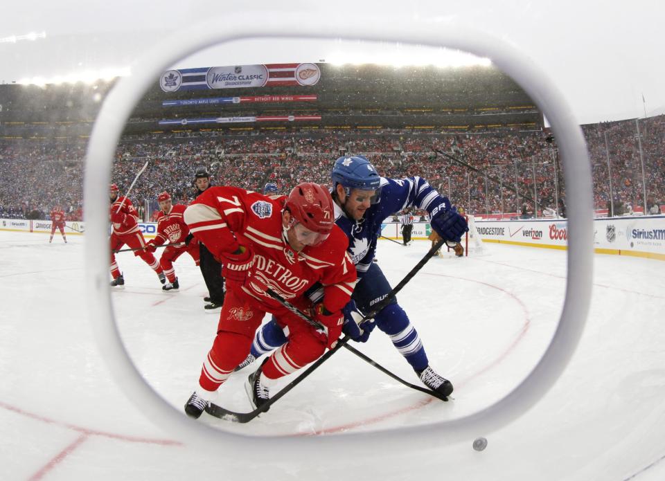 Framed by cutout in the safety glass, Detroit Red Wings right wing Daniel Cleary (71) and Toronto Maple Leafs defenseman Cody Franson (4) battle for the puck during the third period of the Winter Classic outdoor NHL hockey game at Michigan Stadium in Ann Arbor, Mich., Wednesday, Jan. 1, 2014. (AP Photo/Paul Sancya)