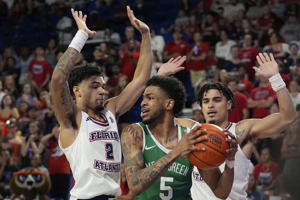 North Texas guard Rondel Walker (5) looks for an opening past Florida Atlantic guards Nic Boyd (2) and Bryan Greenlee, right, during the second half of an NCAA college basketball game, Sunday, Jan. 28, 2024, in Boca Raton, Fla. (AP Photo/Wilfredo Lee)