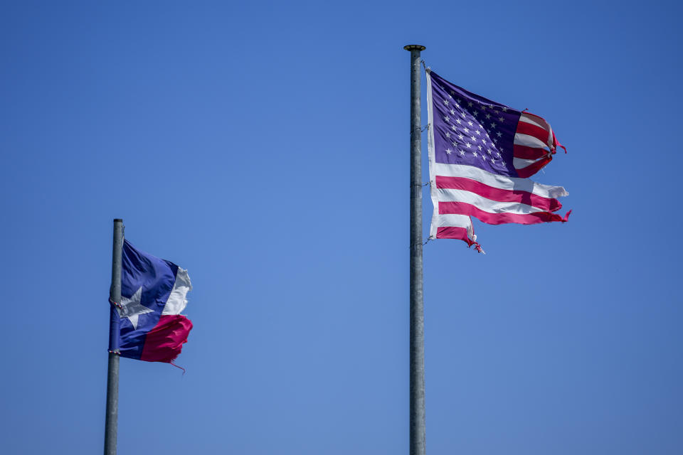 A battered Texas and U.S. flags are visible the morning after a deadly tornado rolled through, Sunday, May 26, 2024, in Valley View, Texas. Powerful storms left a wide trail of destruction Sunday across Texas, Oklahoma and Arkansas after obliterating homes and destroying a truck stop where drivers took shelter during the latest deadly weather to strike the central U.S. (AP Photo/Julio Cortez)