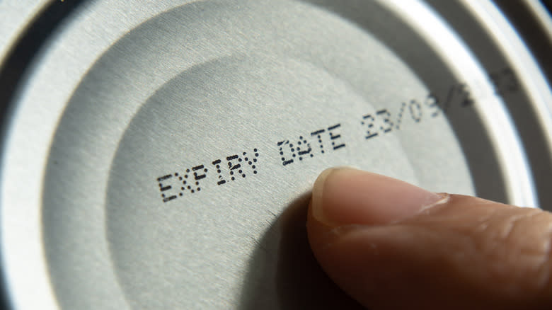 Finger pointed to expiry date on can