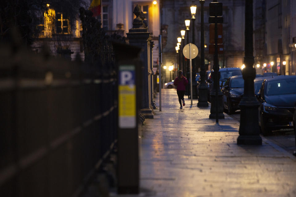 A woman jogs down a street in the early morning outside the UK ambassadors residence in Brussels, Monday, Dec. 21, 2020. The United Kingdom and the European Union were continuing on Monday a "last attempt" to clinch a post-Brexit trade deal, with EU fishing rights in British waters the most notable remaining obstacle to avoid a chaotic and costly changeover on New Year. (AP Photo/Virginia Mayo)