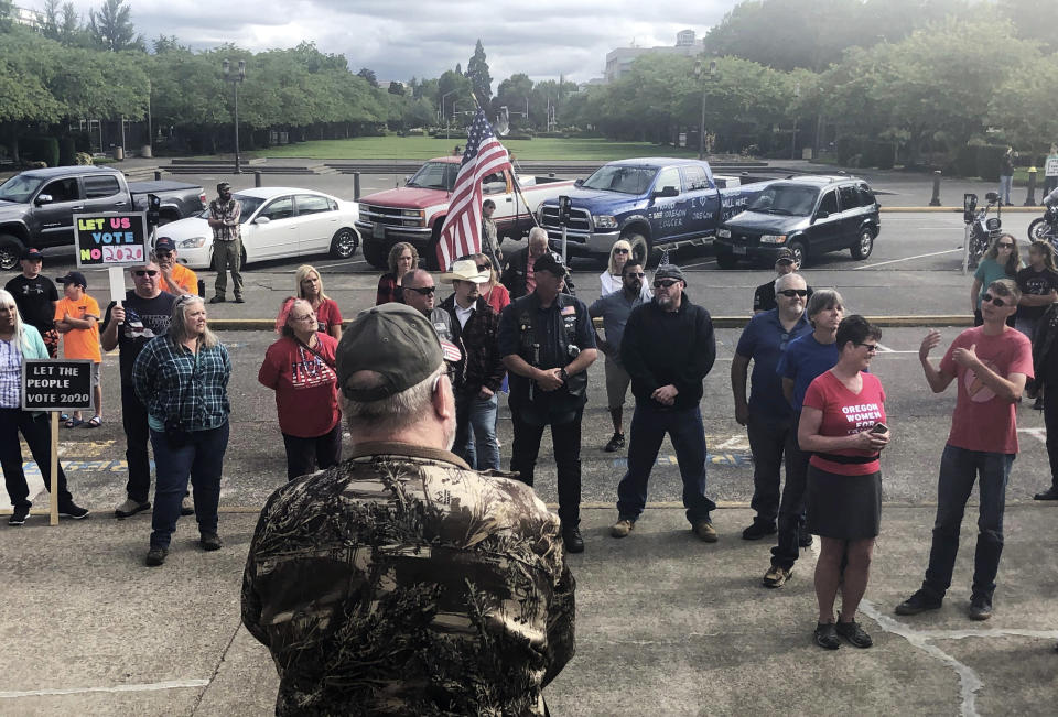 In this photo taken Sunday, June 23, 2019, a small crowd of local Republicans show their support of a Republican walkout outside the Oregon State Capitol in Salem, Ore. The gathering took place only a day after the Senate President ordered the statehouse to close over a "possible militia threat," the latest escalation in a Republican walkout over proposed climate policy that has put Democrats' top legislative priorities at risk. (AP Photo/Sarah Zimmerman)