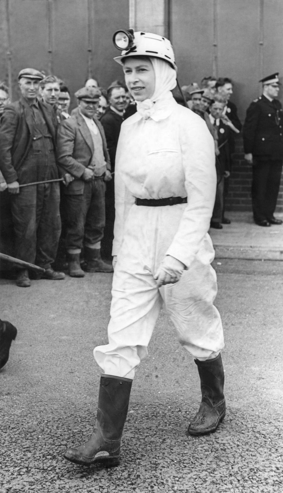 1958: Miners see the Queen wearing white overalls, scarf and helmet and black gumboots during her visit to Rothes Colliery Fifeshire. It was the Queen;s first visit to a coal mine and she spent about half an hour underground visiting the coal face (PA)
