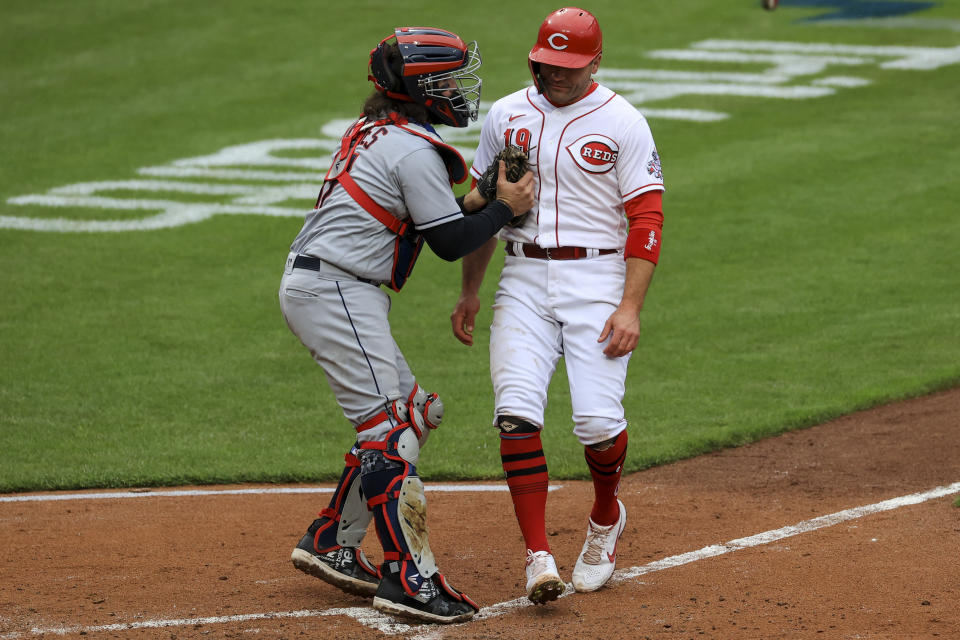 Cleveland Indians' Austin Hedges, left, tags out Cincinnati Reds' Joey Votto at home plate during the fifth inning of a baseball game in Cincinnati, Saturday, April 17, 2021. (AP Photo/Aaron Doster)