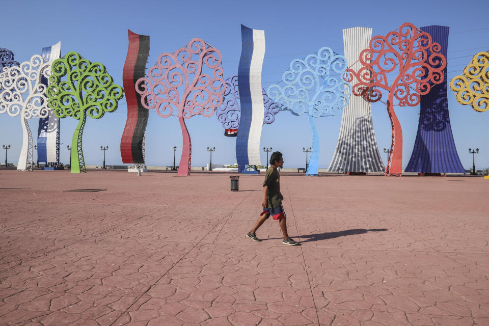 A young man walks in an empty Plaza de la Fe, in Managua, Nicaragua, Tuesday, April 7, 2020. Restaurants are empty, there's little traffic in the streets and beach tourists are sparse headed into Holy Week despite the government's encouragement for Nicaraguans to go about their normal lives. (AP Photo/Alfredo Zuniga)