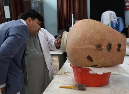 Mohammad Fahim Rahimi, Director of National Museum inspects a pot for restoration at the National Museum in Kabul