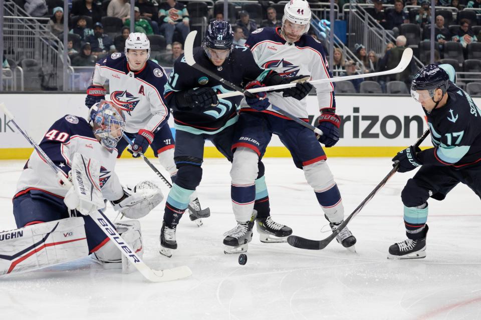 Seattle Kraken center Alex Wennberg (21) and center Jaden Schwartz (17) battle for the puck with Columbus Blue Jackets defenseman Erik Gudbranson (44) and goaltender Daniil Tarasov (40) during the first period of an NHL hockey game, Sunday, Jan. 28, 2024, in Seattle. (AP Photo/John Froschauer)