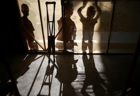 The shadows of crutches and children with special needs are seen during a party for children affected by the Syrian conflict and in need for psychological support, in the rebel held besieged town of Hamouriyeh, eastern Ghouta, near Damascus, Syria, September 29, 2016. REUTERS/Bassam Khabieh