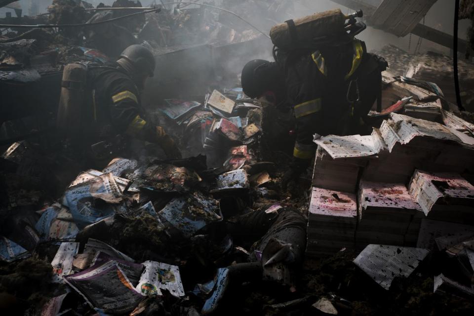 Ukrainian first responders work at the site of a Russian missile attack on a publishing factory in Kharkiv, Ukraine on May 23, 2024. The destroyed books are seen shattered on the ground. (Francis Farrell/The Kyiv Independent)