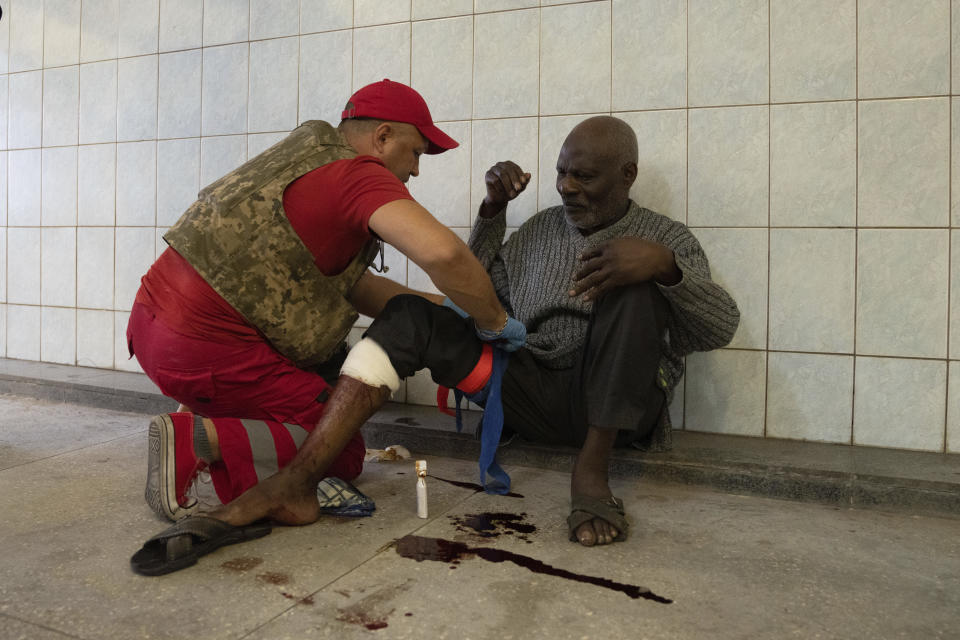 A medical worker treats an injured man after Russian shelling at Barabashovo market in Kharkiv, Ukraine, Thursday, July 21, 2022. (AP Photo/Evgeniy Maloletka)