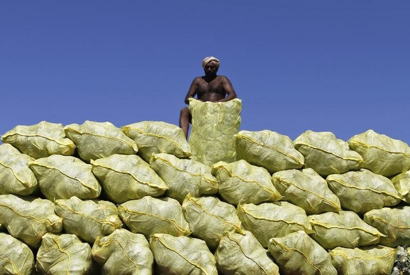 A labourer unloads bags filled with cabbage from a supply truck at a vegetable wholesale market in Chennai August 23, 2013. REUTERS/Babu/Files