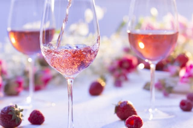 Glass of rosÃ© wine being poured at a picnic setting on a summer's day.