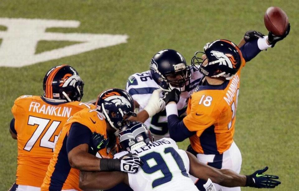 Denver’s Peyton Manning is hit by Seattle’s Cliff Avril (56), a hit that forced a fluttering pass that Malcolm Smith returned for a touchdown during Super Bowl XLVIII.