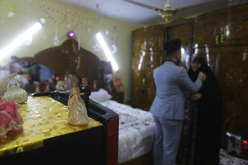 In this Thursday, April 9, 2020 photo, Ahmed Khaled al-Kaabi talks to him mother before his wedding in Najaf, Iraq, hardest hit town by coronavirus in the country with government banned large public gatherings. Unwilling to postpone the wedding, al-Kaabi asked the local security forces to help him wed his beloved. The police responded by providing the groom vehicles blasting music to bring his bride to the family home for a small celebration of just six people. (AP Photo/Anmar Khalil)