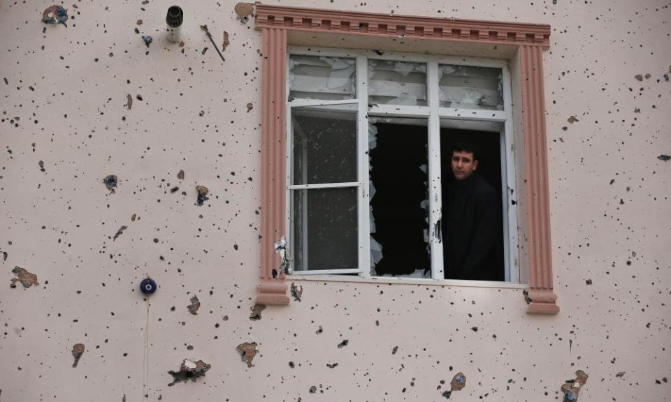 A man looks out of a window damaged by a rocket fired by Kurdish fighters in Syria into the town of Kilis, Turkey.