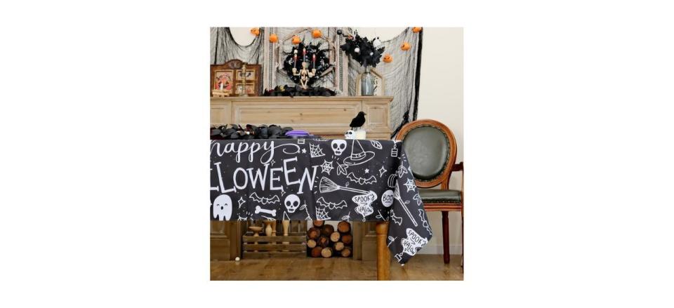 black plastic tablecloth with the words "Happy Halloween" on it and various spooky designs also in white