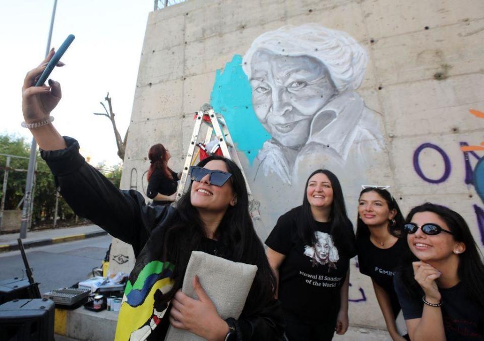 Unas chicas se hacen un selfi con un mural de Nawal el Saadawi en Líbano.