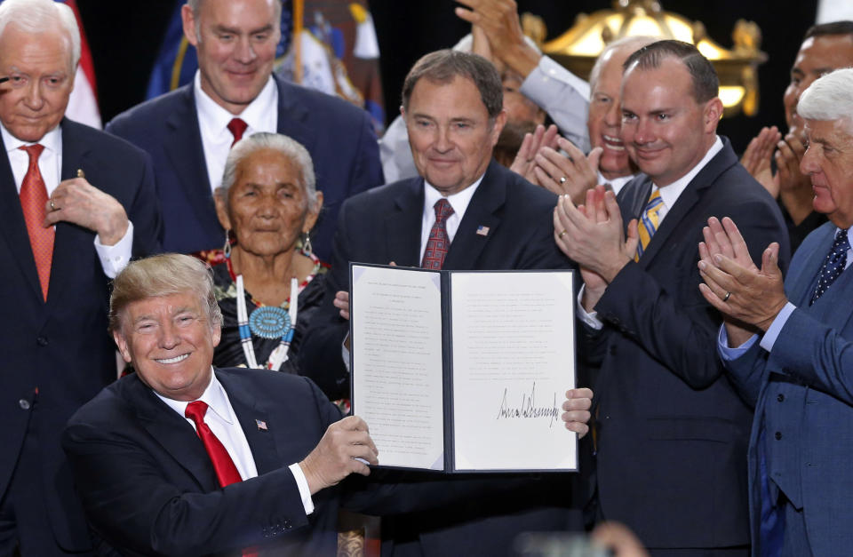 FILE - In this Monday, Dec. 4, 2017, file photo, President Donald Trump holds up a signed proclamation to shrink the size of Bears Ears and Grand Staircase Escalante national monuments, at the Utah State Capitol, in Salt Lake City. The U.S. government is unveiling its final management plan for the Bears Ears National Monument on tribal lands home to ancient cliff dwellings and other artifacts in Utah that was significantly downsized by President Trump. Conservation groups, tribes and an outdoor retail company have sued challenging the downsizing. (AP Photo/Rick Bowmer, File)