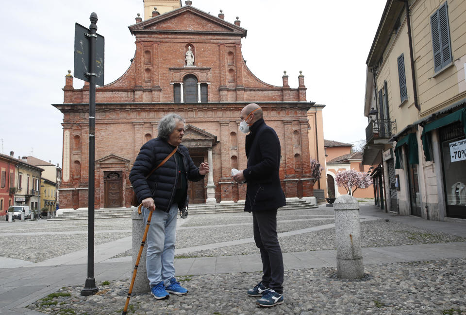 In this photo taken on Thursday, March 12, 2020, Codogno's mayor Francesco Passerini, right, talks to a citizen in Codogno, Italy. The northern Italian town that recorded Italy’s first coronavirus infection has offered a virtuous example to fellow Italians, now facing an unprecedented nationwide lockdown, that by staying home, trends can reverse. Infections of the new virus have not stopped in Codogno, which still has registered the most of any of the 10 Lombardy towns Italy’s original red zone, but they have slowed. For most people, the new coronavirus causes only mild or moderate symptoms. For some it can cause more severe illness. (AP Photo/Antonio Calanni)