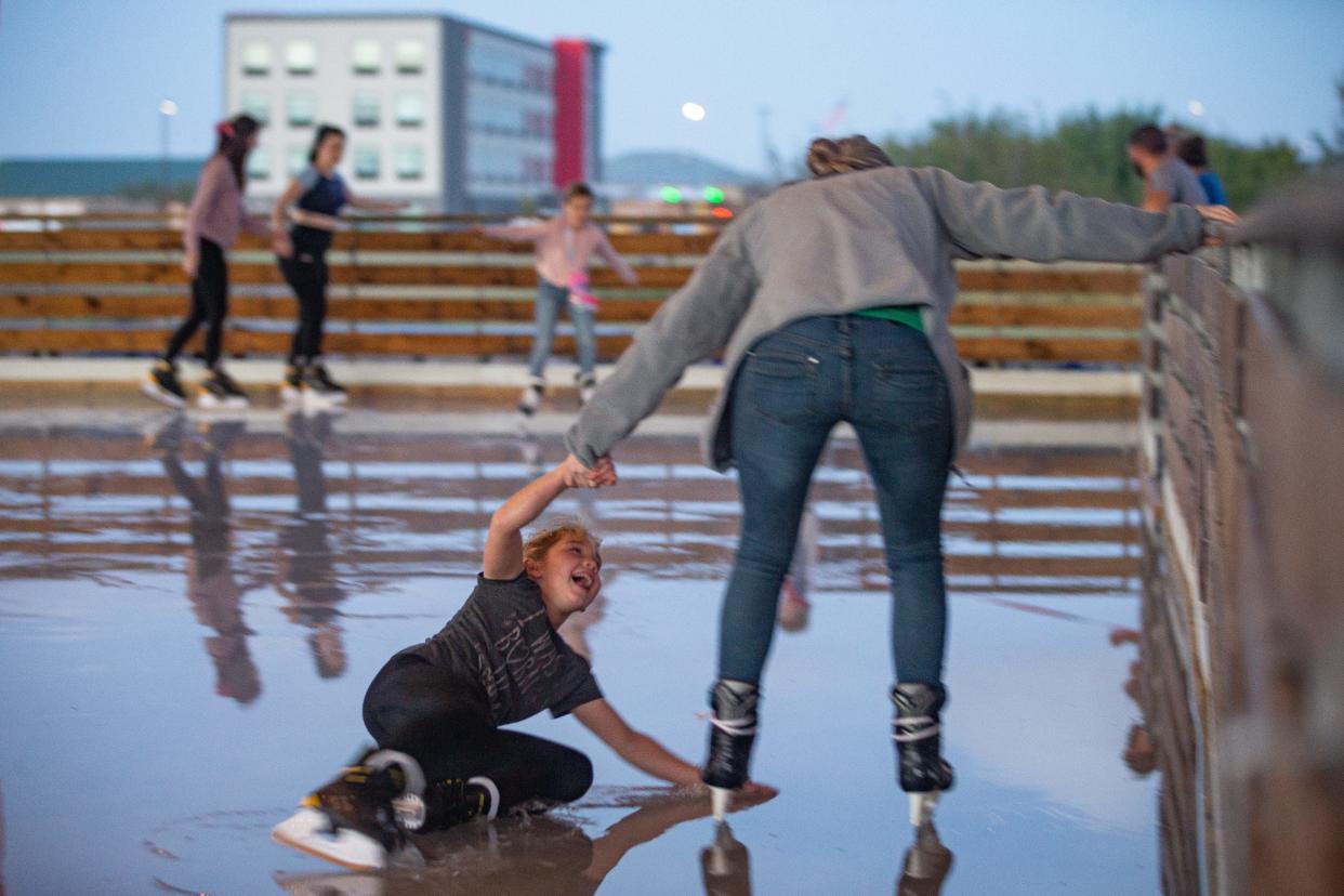 Julie Rogers helps Sawyer Rubreckt, 7, up after falling while ice skating at the Portland Community Center Pavilion, Dec. 16, 2021, in Portland, Texas.