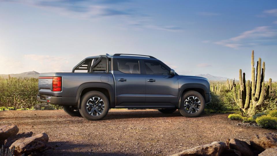 A blue BYD Shark hybrid pickup truck is parked in the desert.