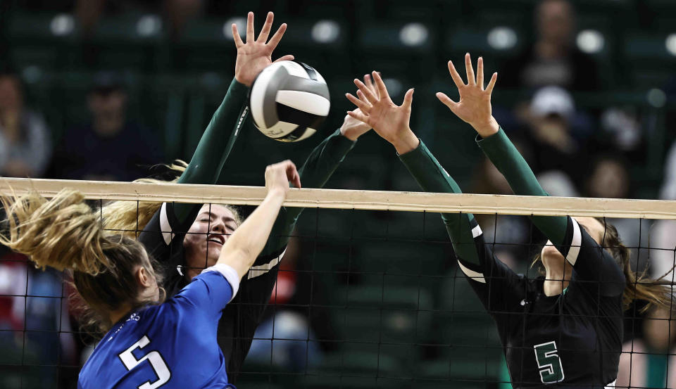 Gilmore Academy's Kayla Channell, in blue, attempts a kill against Badin's defenders in the state semfinal Nov. 11, 2022.